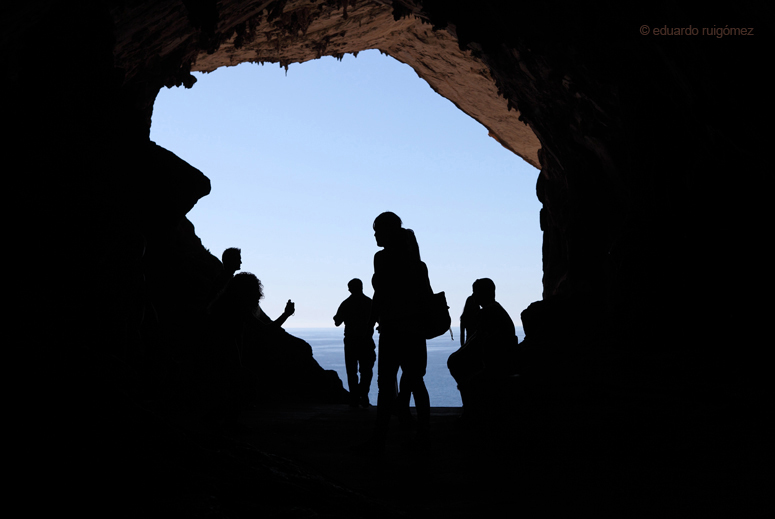 Siluetas de personas a la salida de una cueva en Mallorca. Al fondo, el mar Mediterráneo.