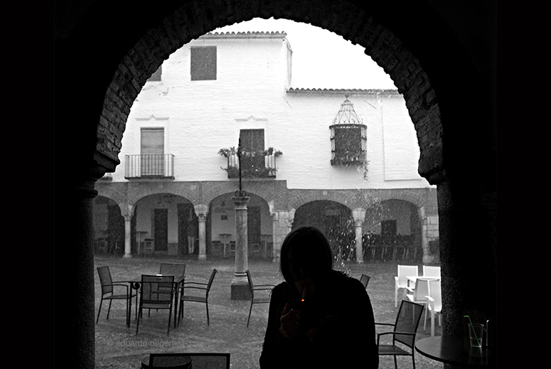 Mujer a contraluz refugiándose de la lluvia.