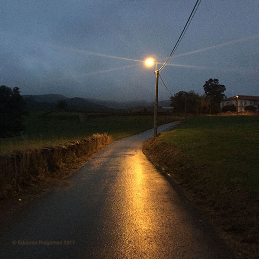 Una farola alumbra un camino por el campo.