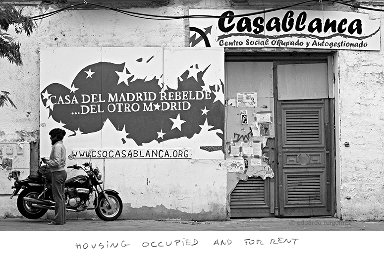 Mujer con una moto frenta a la fachada  de un edificio habitada por personas del movimiento Ocupa.